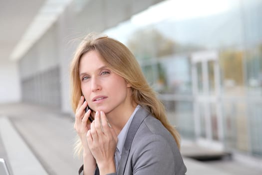 Businesswoman on the phone in front of modern building