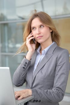 Businesswoman on the phone in front of modern building