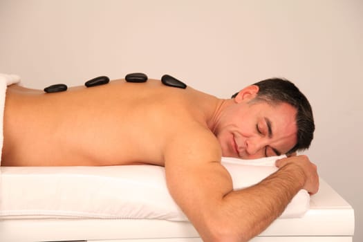 Man laying on massage bed with hot stones on his back