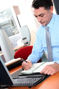 Businessman at his desk writing down on his agenda