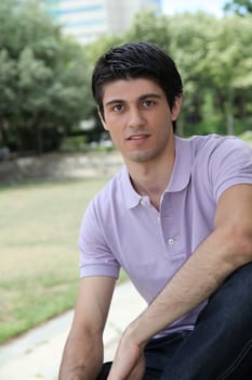 Closeup of young man sitting in a park
