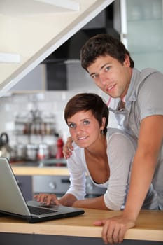 Young couple standing in kitchen with laptop