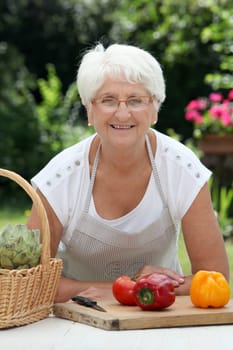Closeup of elderly woman in garden with basket of fresh vegetables