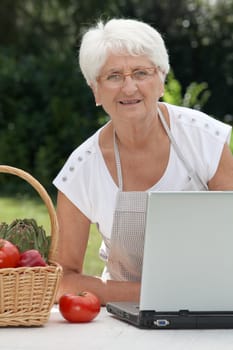 Closeup of elderly woman in garden with basket of fresh vegetables