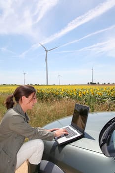 Agronomist with computer in field with wind turbines