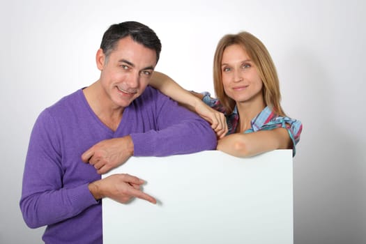 Happy couple showing white message board