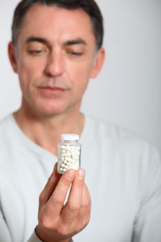 Closeup of man holding bottle of pills