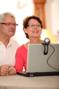 Closeup of senior couple sending messages through webcam