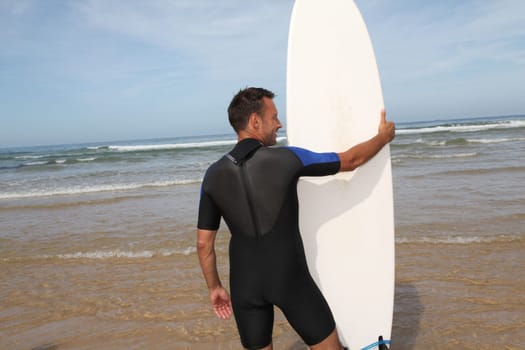 Man standing in water with surfboard