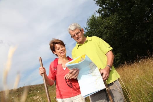 Senior couple rampling in countryside with map