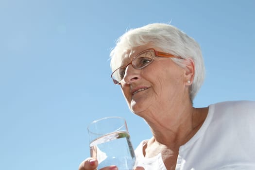 Closeup of elderly woman drinking water from a glass