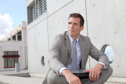 Salesman sitting cross-legged in front of building