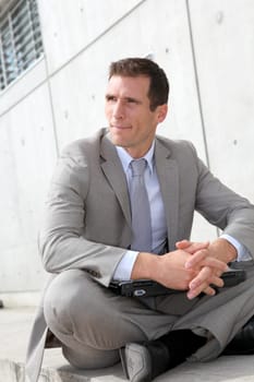 Salesman sitting cross-legged in front of building