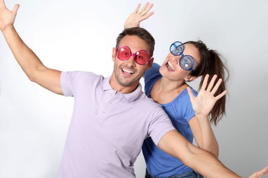 Couple wearing colored glasses having fun on white background