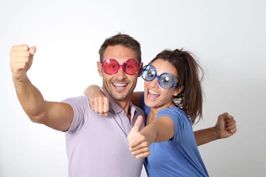 Couple wearing colored glasses having fun on white background