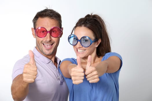 Couple wearing colored glasses having fun on white background