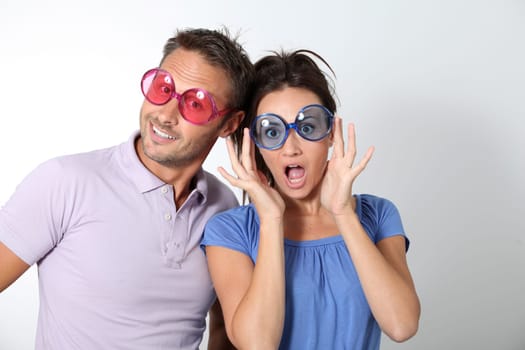 Couple wearing colored glasses having fun on white background