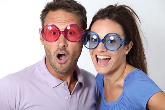 Couple wearing colored glasses having fun on white background