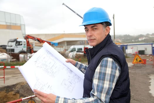 Engineer on construction site with building plan
