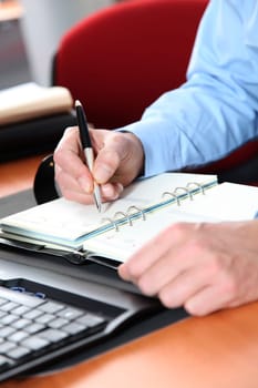 Closeup of man writing on agenda
