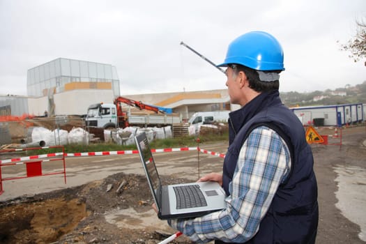 Engineer on construction site with laptop computer