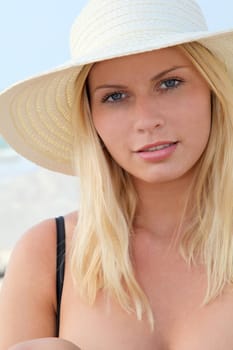 Closeup of beautiful blond woman wearing hat at the beach