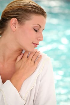 Beautiful woman with bathrobe standing by spa pool