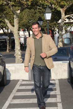Man crossing the street in town on crosswalk