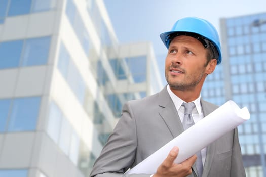 Engineer in front of modern building with plan