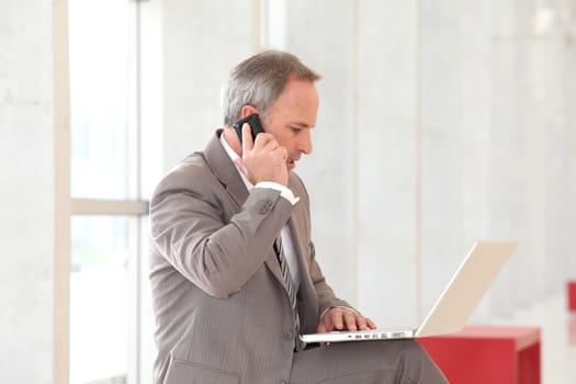Businessman with laptop computer waiting in hall