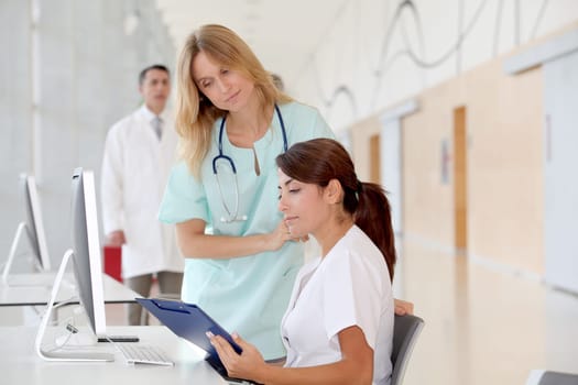 Nurse with intern working in front of computer