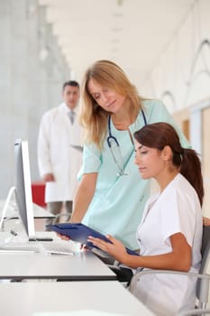 Nurse with intern working in front of computer