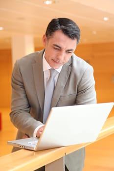 Businessman with laptop computer waiting in hall
