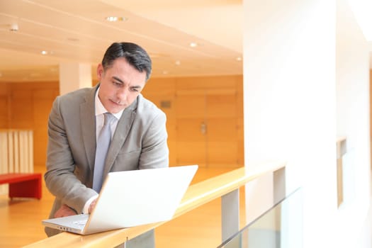 Businessman with laptop computer waiting in hall