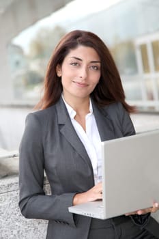 Businesswoman with laptop computer standing outside