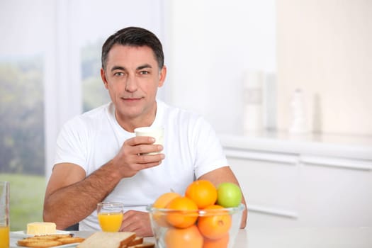 Smiling adult man having breakfast