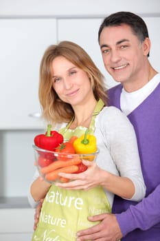 Couple in kitchen with bowl of vegetables