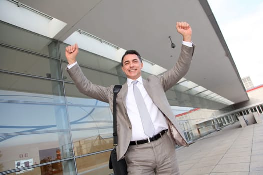 Smiling businessman with arms up