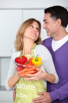 Couple in kitchen with bowl of vegetables