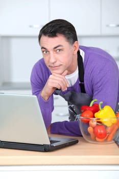 Man in kitchen with laptop computer