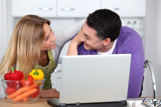 Couple in kitchen looking for cooking receipe