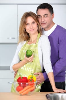 Couple in kitchen with bowl of vegetables