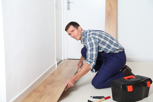 Closeup of artisan installing flooring in room