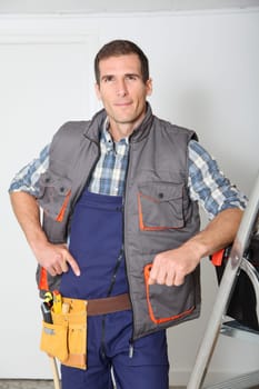 Smiling electrician man standing by scale