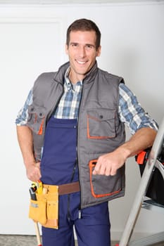 Smiling electrician man standing by scale