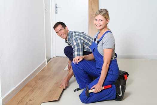 Closeup of artisan installing flooring in room