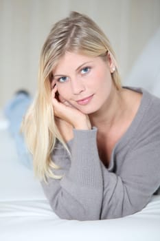 Smiling beautiful blond woman laying on sofa