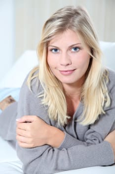 Smiling beautiful blond woman laying on sofa