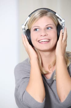 Beautiful blond woman at home with headphones on