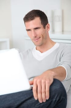 Closeup of adult man sitting on sofa with laptop computer